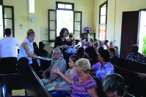 Caption: Pam De Laureal and Aimee Bell, two members of St. Charles Avenue Presbyterian Church in New Orleans, offer copies of Vengan a Las Aguas (the Spanish-language version of Come to the Waters) to members of El Fuerte church in Cuba. Photo by Michael Bell