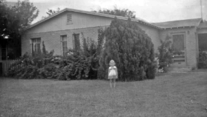 Joy Durrant, as a child, stands in front of her family's first home.