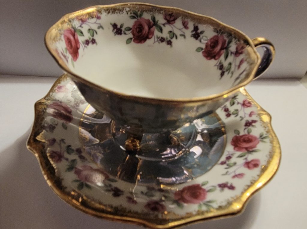 white teacup with gold rim and pink floral pattern sits on matching saucer